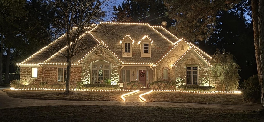 Warm white ground stake lights lining a snow-covered driveway up to a lit home