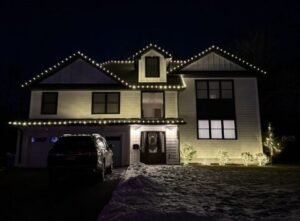 Short Hills NJ home with roofline C9 lights and lighted shrubs in the snow