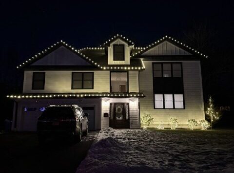 Short Hills NJ home with roofline C9 lights and lighted shrubs in the snow
