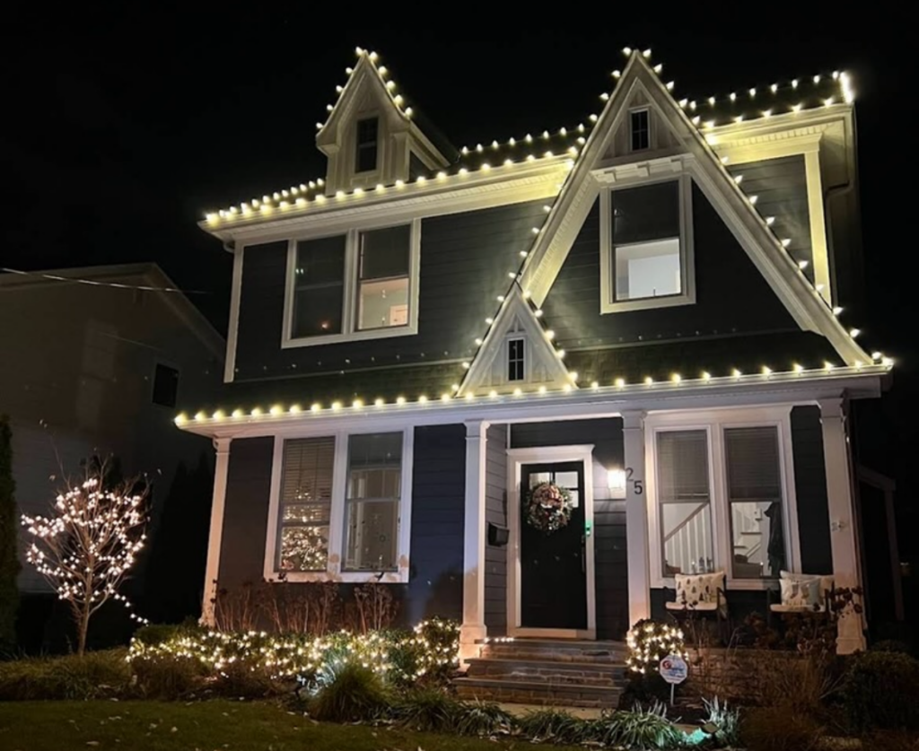 Short Hills NJ home with roofline C9 lights, lighted shrubs and a wreath on the front door