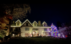 Tudor estate in Short Hills NJ with roofline lights and a multicolor lit Christmas tree on the lawn