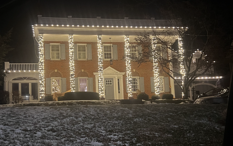Brick Short Hills NJ home with column-wrapped Christmas lights and roofline C9 bulbs in the snow