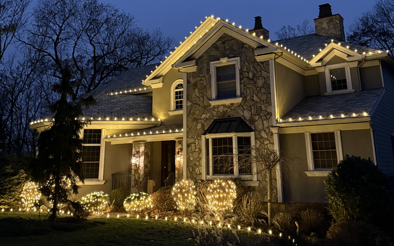 Stone-front Short Hills NJ home with C9 roofline lights and glowing lighted bushes