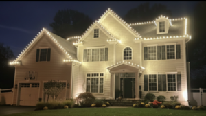 Short Hills NJ home with peaked roofline C9 lights and lit garden beds at night