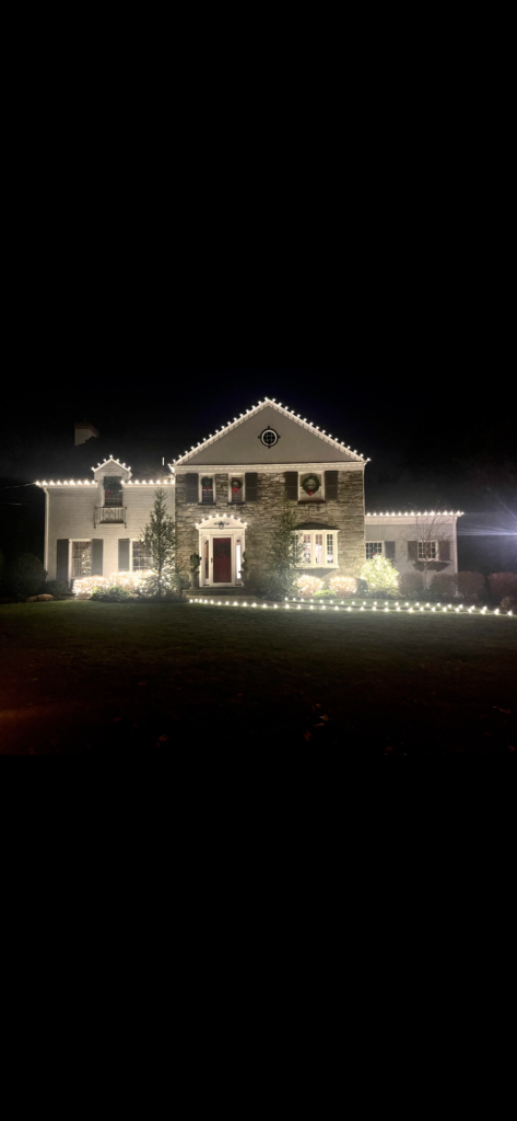 Short Hills NJ colonial with roofline Christmas lights and a lighted walkway across the lawn