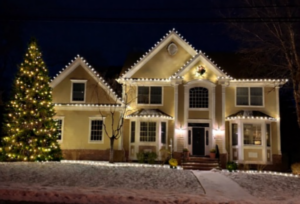Short Hills NJ home with roofline lights and a fully lit Christmas tree on the snowy lawn