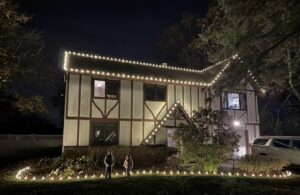 Kids in front of a Short Hills NJ Tudor home lit with C9 roofline and pathway Christmas lights