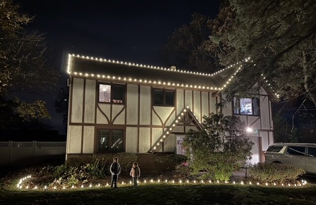 Kids in front of a Short Hills NJ Tudor home lit with C9 roofline and pathway Christmas lights