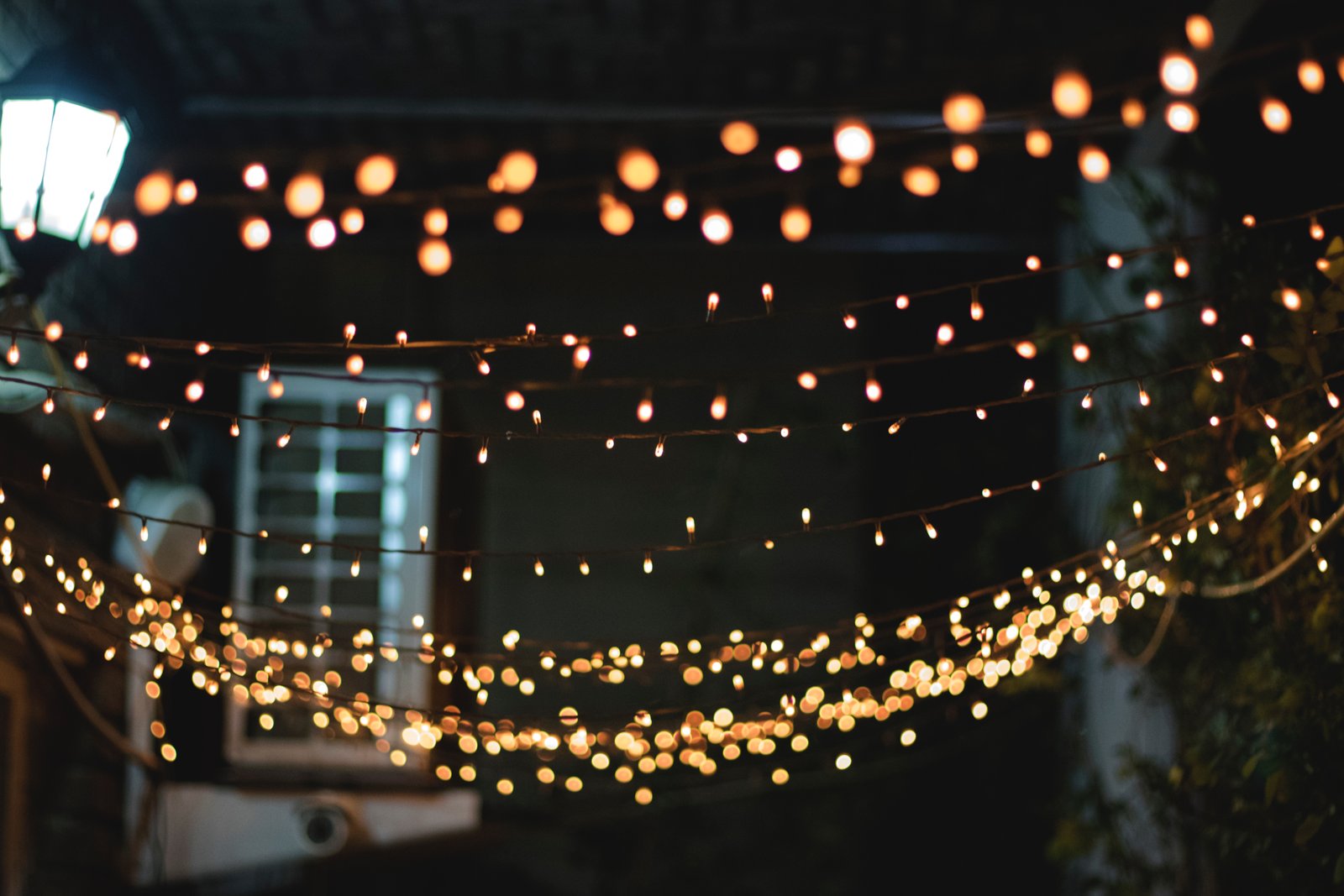 Strands of warm white cafe string lights hung above a patio at night